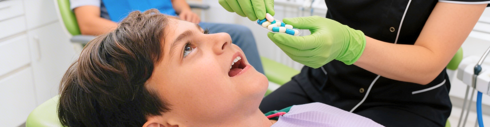 Gloved hands holding sedation pills in front of boy's mouth.